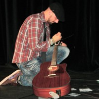 Paul Hilger repariert seine Gitarre während des Auftritts bei RLP Poetry Slam Landesmeisterschaft 2014 Eröffnungsgala. - 5VIER