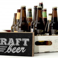 Craft beer bottles in a wooden box with a chalk sign. - 5VIER