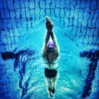 Ein Schwimmer taucht nach dem Startsprung mit gestreckten Armen ins Wasser ein. Sicht von unten. Foto: pexels