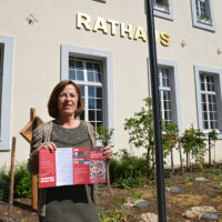 Bürgermeisterin Elvira Garbes präsentiert den Info-Flyer für die Solidarkarte vor dem Trierer Rathaus. Foto: Presseamt Trier
