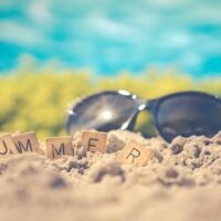 Sonnenbrille Strand- Sonnenbrille im Sand, davor Schriftzug Summer auf Dominosteinen . Foto von Ylanite Koppens von Pexels