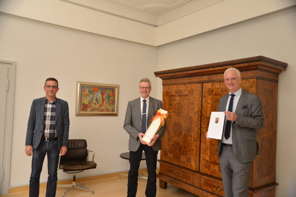 OB Wolfram Leibe (r.) und Dezernent Thomas Schmitt (l.) gratulieren Professor Michael Embach zum 40-jährigen Dienstjubiläum. Foto: Presseamt Trier
