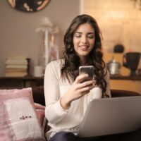 Junge Frau beim Online Dating mit Mobilfon und Notebook - Foto von Andrea Piacquadio von Pexels