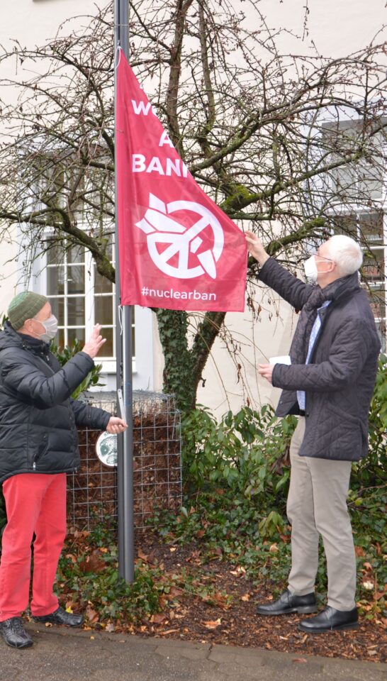 OB Wolfram Leibe (r.) hisst mit Unterstützung von Alois Barra die Flagge der Internationalen Kampagne zum Verbot von Atomwaffen (ICAN) vor dem Rathaus. Bildquelle: Presseamt Trier