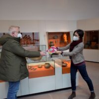 Der erste Besucher erhält den neuen Kurzführer durchs Museum von der stellvertretenden Direktorin Mechthild Neyses-Eiden. Bildquelle: GDKE-Rheinisches Landesmuseum Trier, Franz Stark