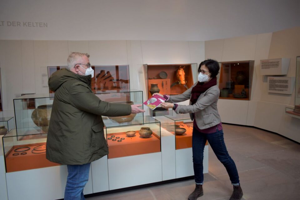 Der erste Besucher erhält den neuen Kurzführer durchs Museum von der stellvertretenden Direktorin Mechthild Neyses-Eiden. Bildquelle: GDKE-Rheinisches Landesmuseum Trier, Franz Stark