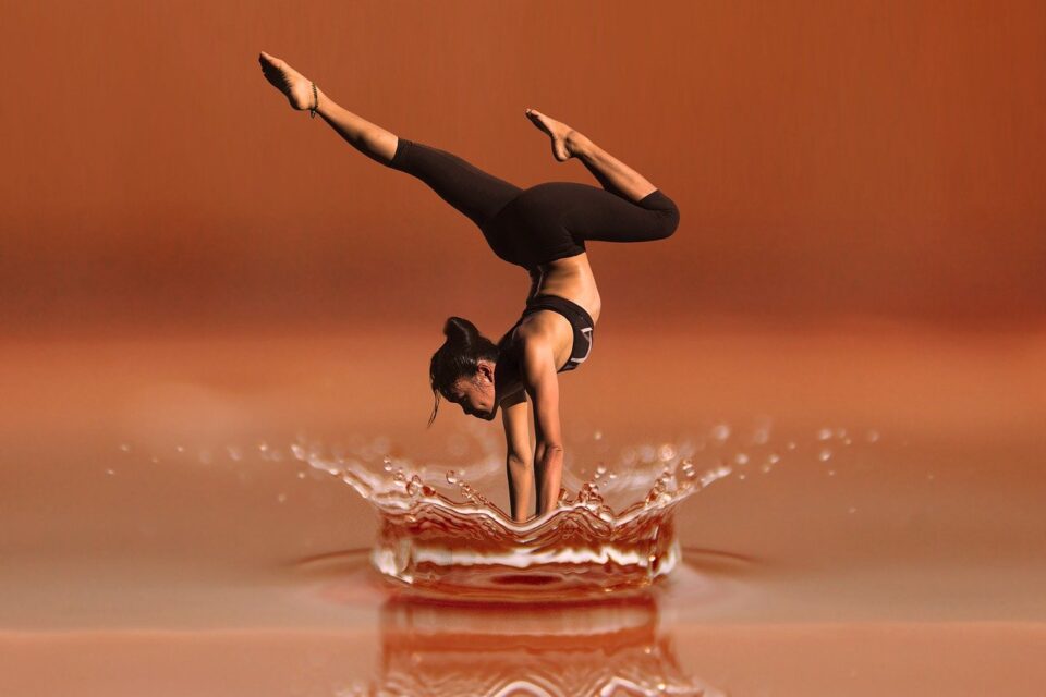 Eine Tänzerin macht einen künstlerischen Handstand in einer Wasserlache. Foto: Bild von Gerd Altmann auf Pixabay