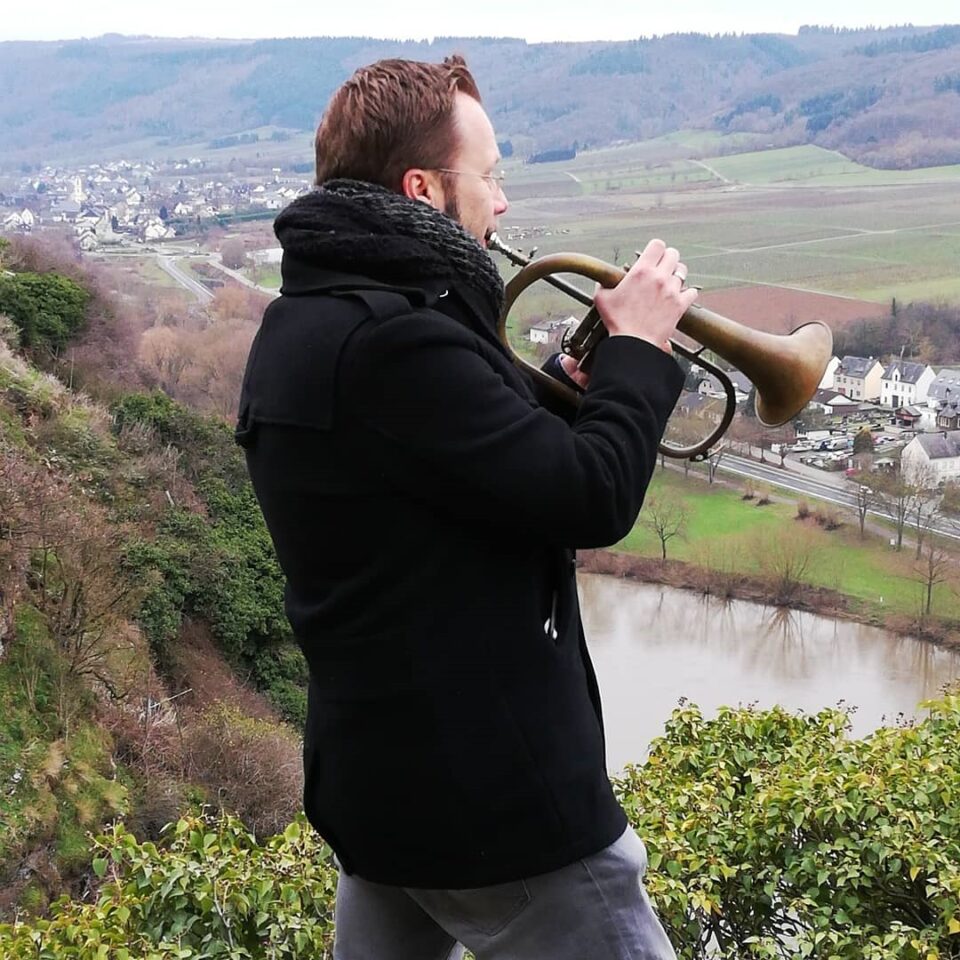 Das Foto zeigt den Trompeter Daniel Ackermann mit dem Flügelhorn vor der Burgruine Landshut in Bernkastel-Kues © Regionalinitiative „Faszination Mosel“
