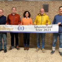 Die Vorstandsmitglieder Claus Sporer, Ralf Thiex, Pia Bösen, Hans Tilly und Norbert Ruschel (von links) präsentieren das Zielband für den Bitburger-0,0%-Lauf der Asse. Bildquelle: Silvesterlauf Trier e.V.
