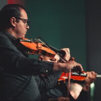 Sinnbild - Streicher spielen Violine. Quelle: Gabriel Santos auf Pexels.