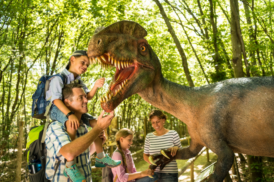 Eine Familie bestaunt im Dinopark Teufelsschlucht einen Dilophosaurus. Foto: Dominik Ketz.