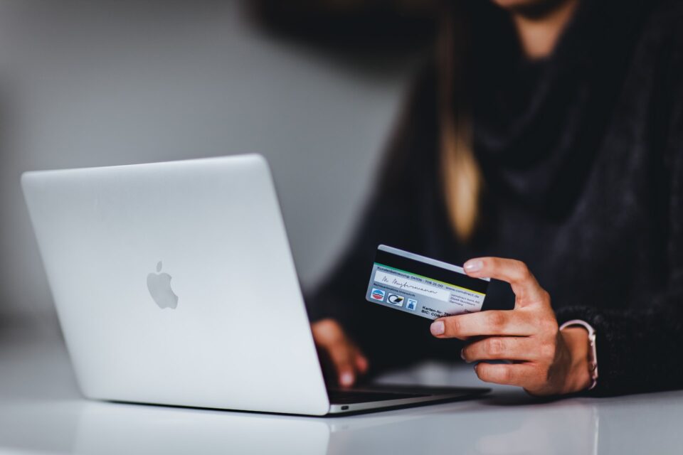 Auf dem Foto nutzt eine Frau ihre Kreditkarte an einem Macbook zur Onlinezahlung. Foto:  Pickawood on unsplash