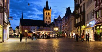 Der Trierer Hauptmarkt aus Richtung Porta nachts mit Menschen am Weinstand und der Kirche im Hintergrund. Foto: neufal54 /pexels.com