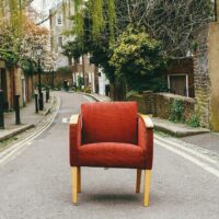 Ein roter Polsterstuhl steht mitten auf einer kleinen Straße. Foto: pixaby und pexels