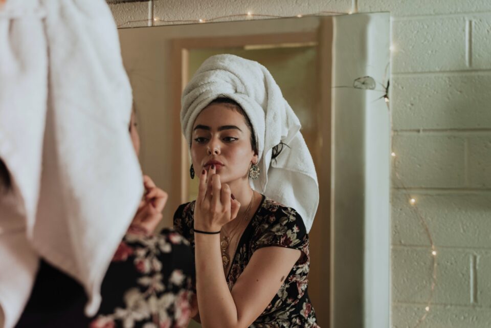 Eine Frau schminkt sich vor dem Spiegel. Foto: Photo by kevin laminto on Unsplash