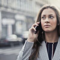 Warnung vor Betrügern am Telefon: Frau im Anzug erhält Anruf und schaut skeptisch. Foto: Andrea Piacquadio/pexels