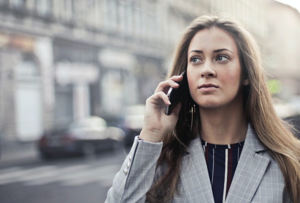 Warnung vor Betrügern am Telefon: Frau im Anzug erhält Anruf und schaut skeptisch. Foto: Andrea Piacquadio/pexels
