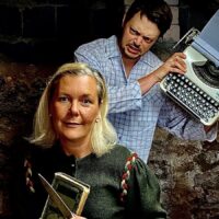 Ein Mann steht mit einer Schreibmaschine hinter einer Frau, die ein Messer und ein Buch in der Hand hält. Foto: Stephan Vanecek