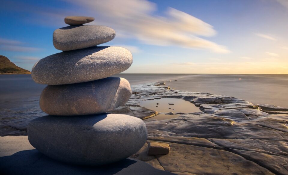 Das Bild zeigt einen Steinstapel am Meer im Nachmittagslicht. Foto: Pixabay via Pexels 