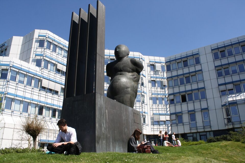 Das Bild zeigt das Psychologie-Gebäude der Universität Trier mit dem Kunstwerk Laokoon von Waldemar Otto im Vordergrund. Foto: Universität Trier