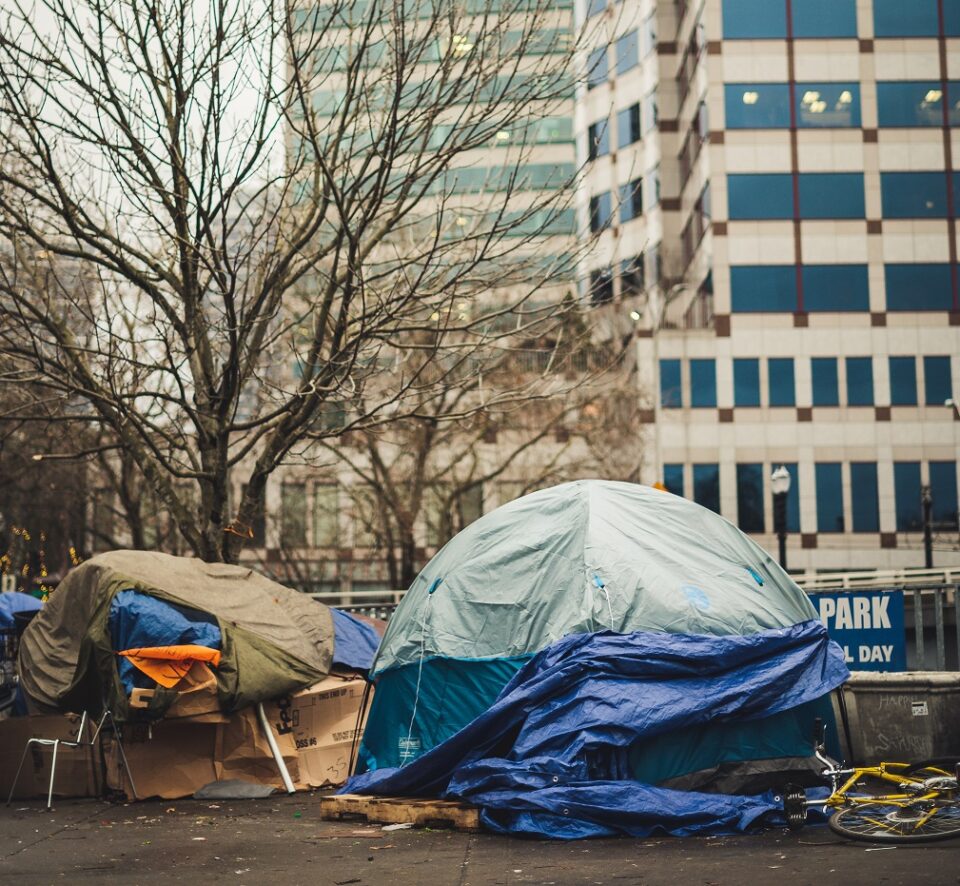Zelte in einer Stadt vor einem Hochhaus. Foto: Brett Sayles/ Pexels