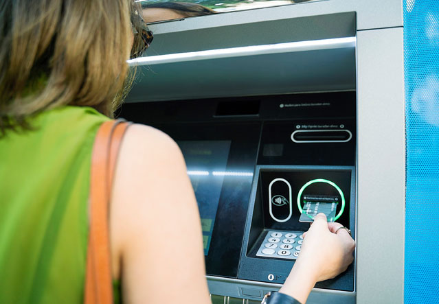 Frau steckt EC-Karte in Bankautomat. Foto: ERGO Group