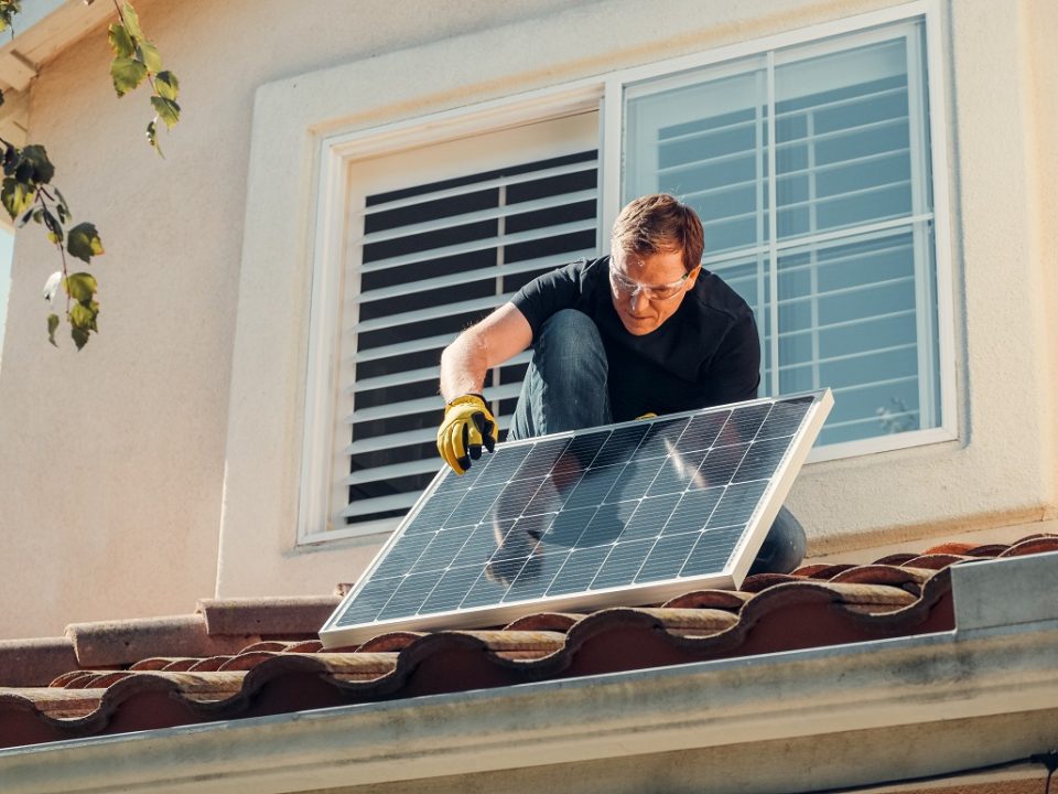Person auf Dach mit einem Photovoltaik-Modul. Foto: KindelMedia/ Pexel