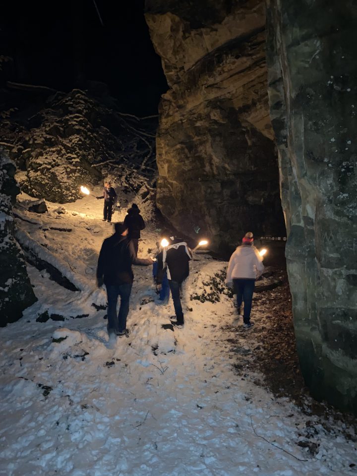 Flackerndes Fackellicht lässt die Felsen der Teufelsschlucht lebendig wirken. Foto: Judith Kronewirth, Felsenland Südeifel Tourismus GmbH